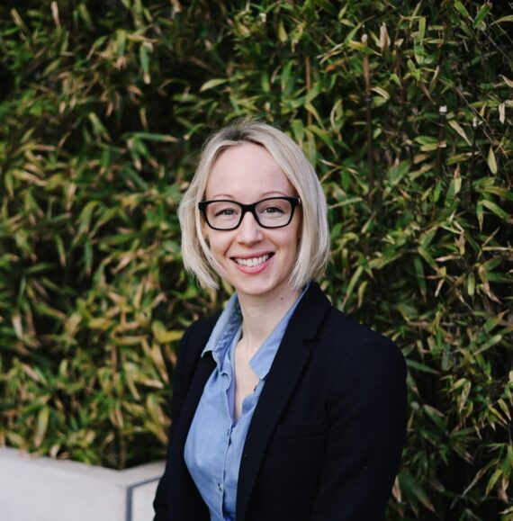 Rebecca wearing a suit siting and smiling